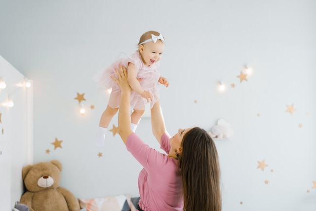 Happy family at home in the nursery. The mother throws the child daughter and laughs