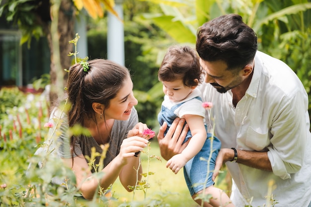 Concetto di famiglia felice a casa insieme, bambini che si divertono con il padre e la madre nel giardino naturale estivo all'aperto, le persone che si divertono, il ragazzo o la ragazza e la giovane donna stanno sorridendo lo stile di vita fuori dal parco