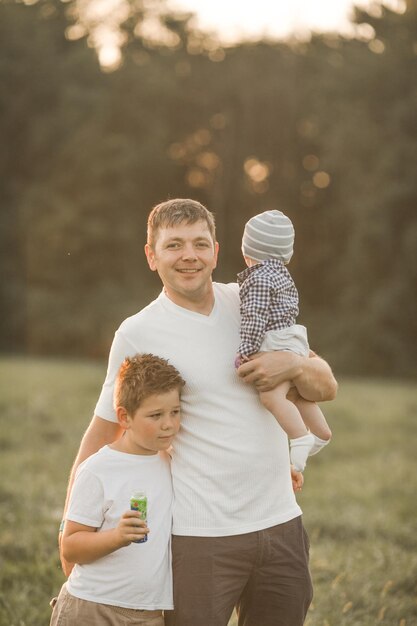 Photo happy family hugging and embracing on summer walk father and his two sons walking in the park and enjoying the beautiful nature cute family portrait