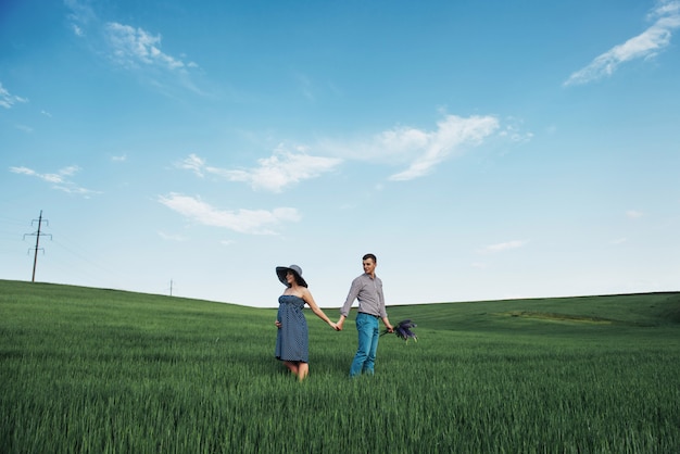 Happy family hugging in a field of green wheat