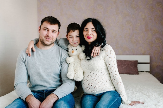 Happy family. Husband, pregnant wife and son at home.