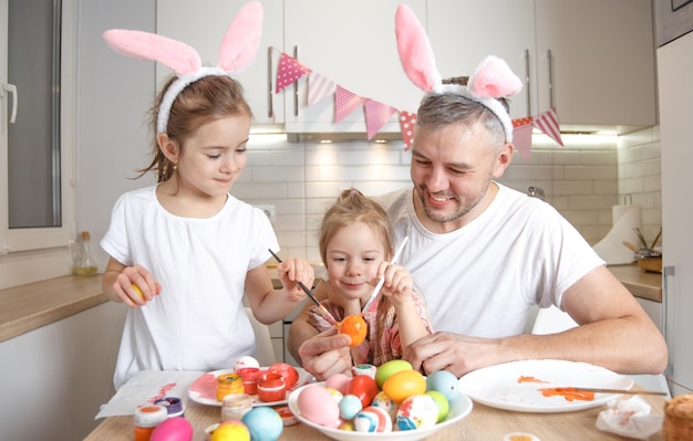 Una famiglia felice si sta preparando per le vacanze di pasqua colorando le uova di pasqua