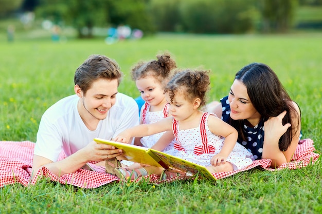 Счастливая семья читает книгу в парке.