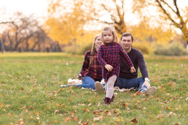 Фото Счастливая семья отдыхает в осеннем лесу. мама, папа и дочка сидят в осеннем парке.