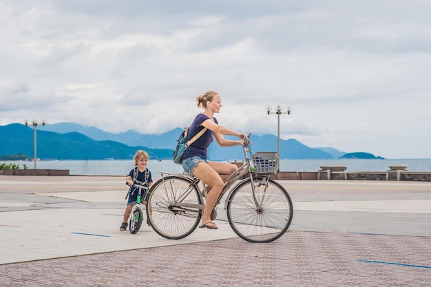 Фото Счастливая семья катается на велосипедах на открытом воздухе и улыбается. мама на велосипеде и сын на беговеле