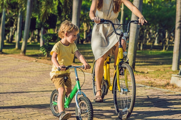 Happy family is riding bikes outdoors and smiling. Mom on a bike and son on a balancebike