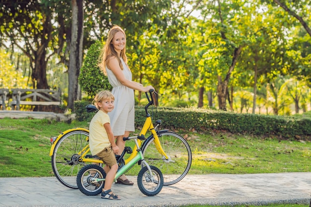 Happy family is riding bikes outdoors and smiling. Mom on a bike and son on a balancebike