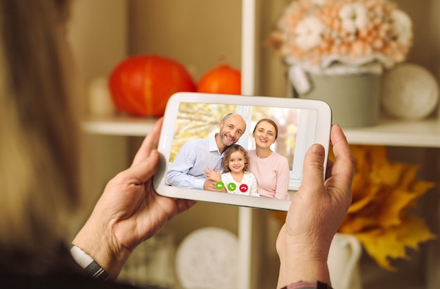 Una famiglia felice sta salutando i propri genitori in una videoconferenza