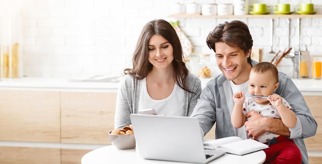a happy family is working from home in their kitchen the father is holding their baby who is chewing