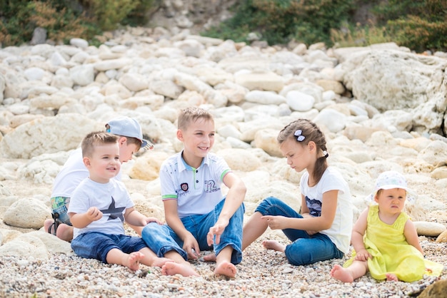 Happy family kids standing on a wood pontoon in front of the sea in summertime.