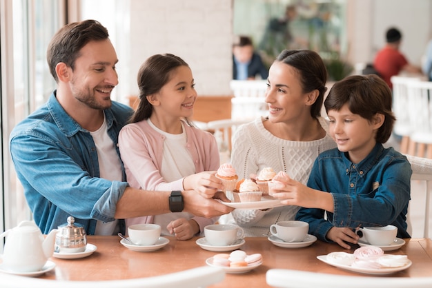 Bambini felici della famiglia che prendono i bigné dal piatto.