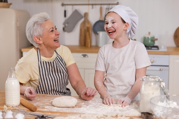 Happy family in kitchen grandmother and granddaughter child cook in kitchen together grandma teachin