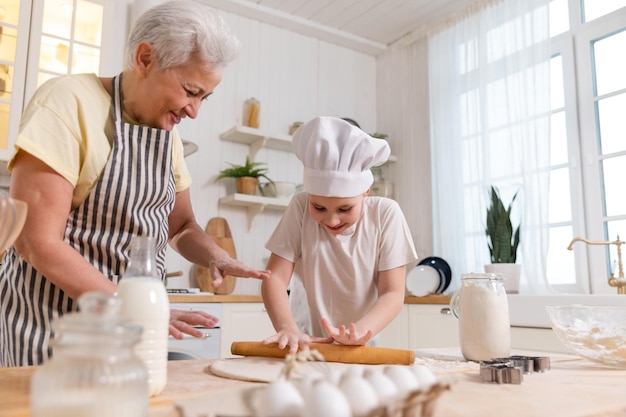 Happy family in kitchen grandmother and granddaughter child cook in kitchen together grandma teachin