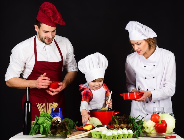 夕食の両親へのシェフの帽子の準備で家の愛らしい子供で台所の健康的な食べ物で幸せな家族