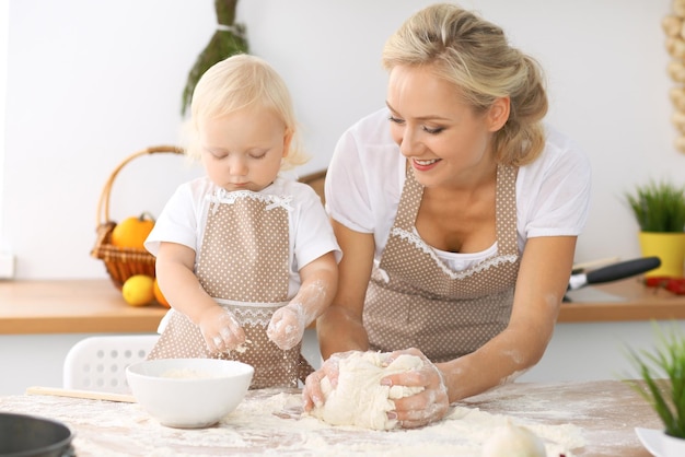 Happy family in the kitchen. Mother and child daughter cooking holiday pie or cookies for Mothers day, casual lifestyle photo series in real life interior