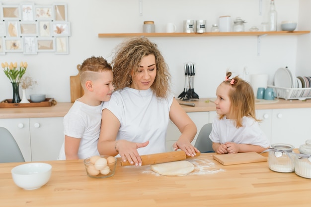 Famiglia felice in cucina. madre e figli preparano la pasta, cuociono i biscotti