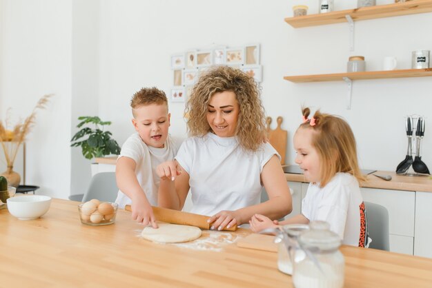 Happy family in the kitchen. mother and children preparing the dough, bake cookies