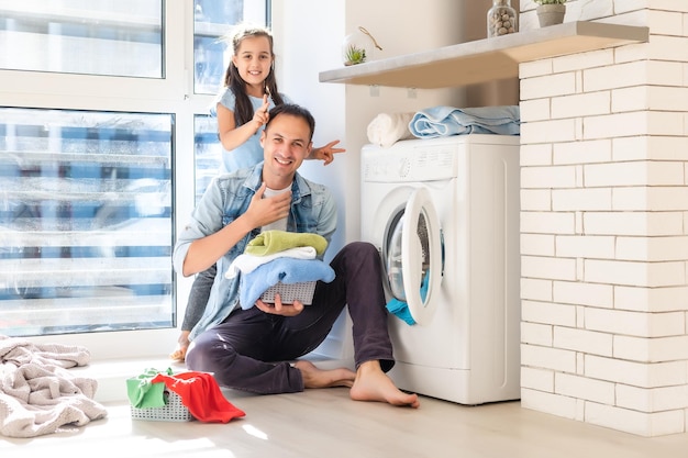 Happy Family laadt kleren in de wasmachine thuis