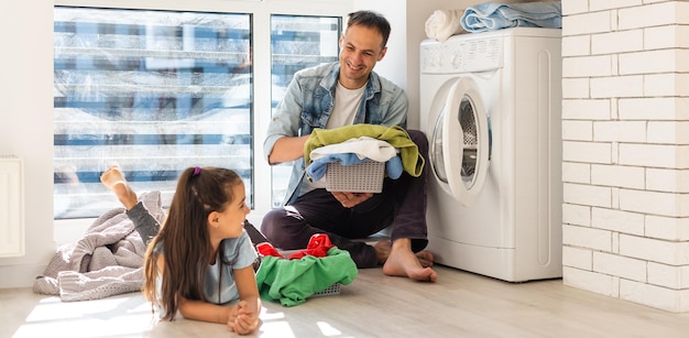 Happy family laadt kleren in de wasmachine thuis