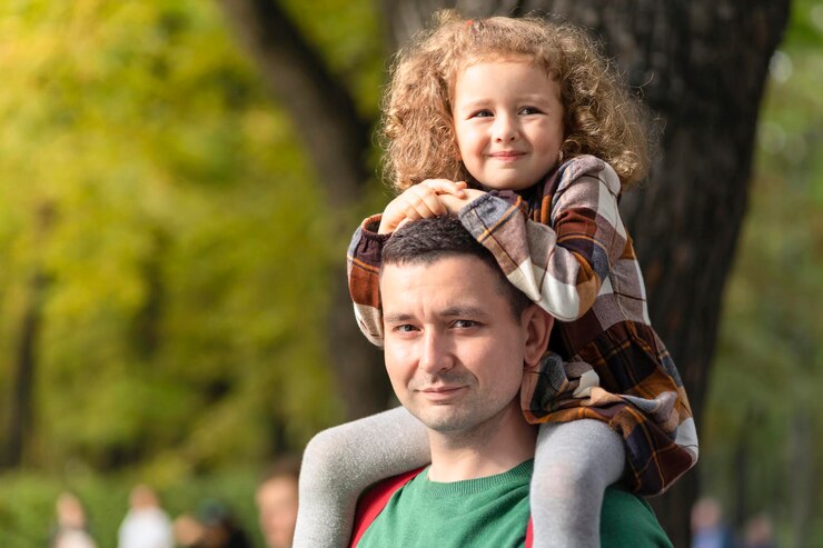 Happy family. laughing daughter sitting on dad shoulders. little girl with father in park. smiling man carrying child