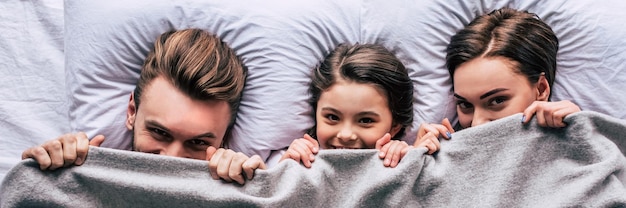 The happy family laying under the blanket