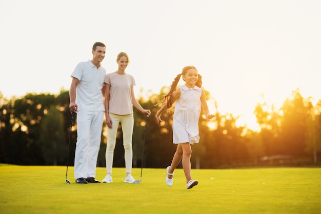 Happy family leisure i golfisti camminano lungo il fairway.