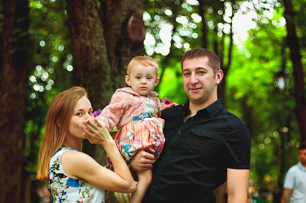 Happy family lifestyle and holiday. mother, father, little girl\
walking in city, green park. fun