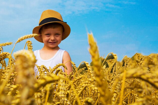 사진 행복한 가족 모자를 쓴 매력적인 행복한 소년이 밀밭에서 웃는다.