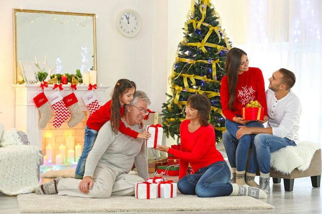 Happy family in living room giving Christmas presents to each other