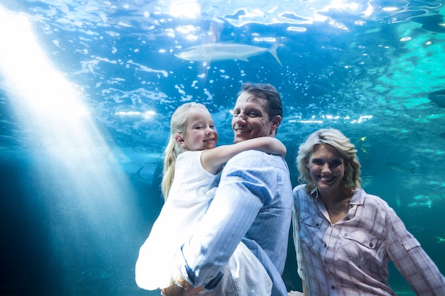 Foto famiglia felice che guarda l'obbiettivo dietro un acquario