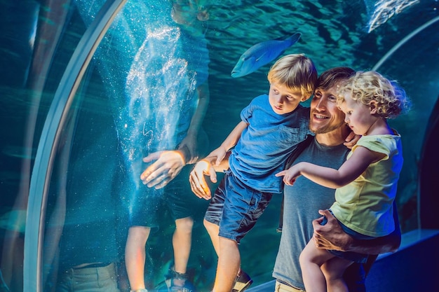 Счастливая семья смотрит на рыбу в туннельном аквариуме