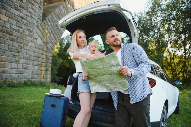 Happy family looking at map next to car