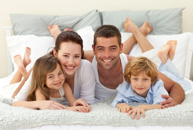 Happy family lying in bed and smiling at the camera