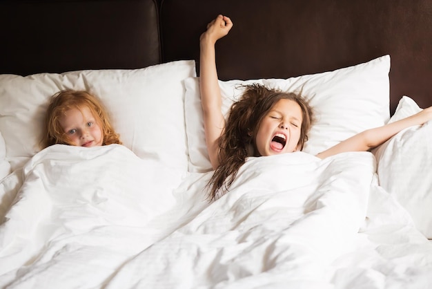 Happy family lying under blanket in bed at home