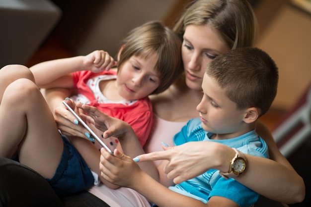 Photo happy family lying down on the sofa and using tablet