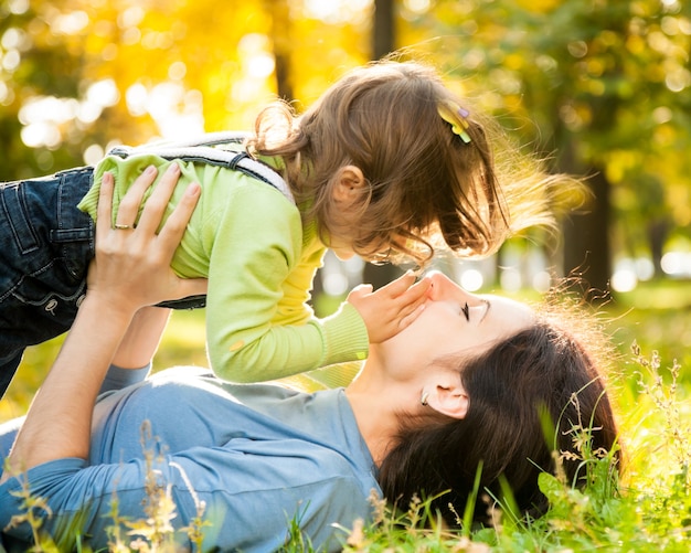 Happy family lying on grass in autumn park