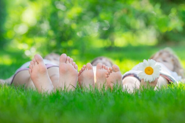 Счастливая семья лежит на зеленой траве Дети веселятся на открытом воздухе в весеннем парке