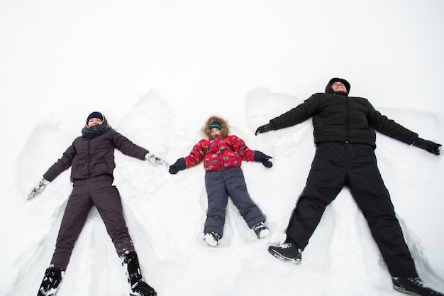 雪の天使を作る雪の中で横たわっている幸せな家族