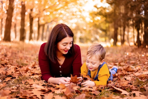 Happy family mom and baby boy play outdoors in nature in the autumn park A little boy and his mother in the autumn park Autumn entertainment for kids