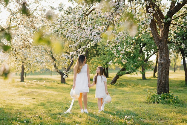 Happy family mom and daughter in a blooming apple orchard in spring