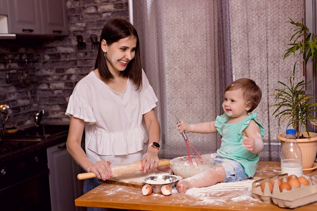 Happy family, mom, daughter play and cook in the kitchen, knead the dough and bake cookies