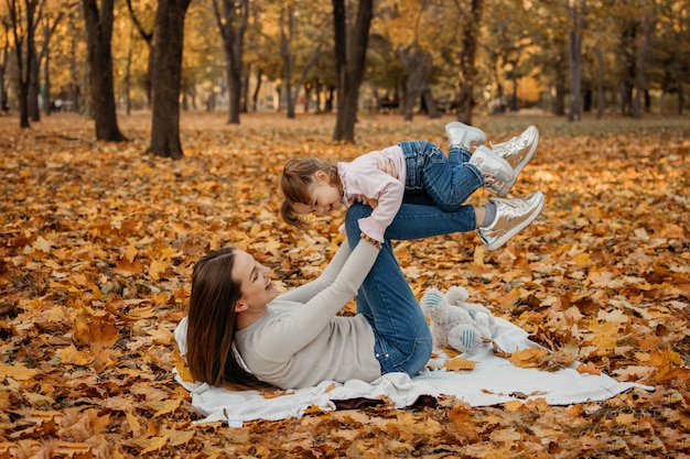 Happy family mom and toddler baby girl playing outdoors in fall park little girl and her mother in