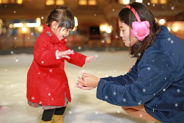 Happy family mother and adorable little girl has a fun in snow, Winter time.