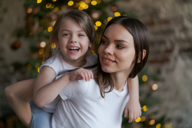 幸せな家族の母親と赤ちゃんの小さな娘がクリスマス休暇のために冬に遊んで