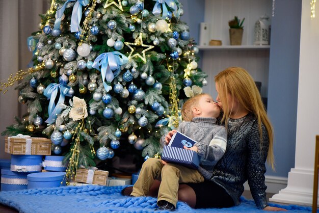 幸せな家族の母親とクリスマス休暇の赤ちゃんの小さな息子の演奏家。新年の休暇。