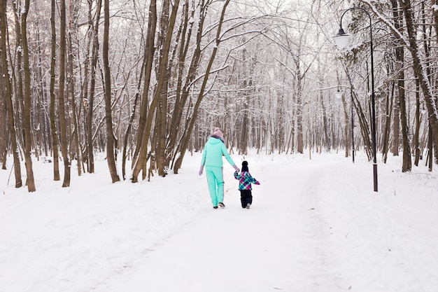 森の中の冬の散歩に幸せな家族の母と子の赤ん坊の娘