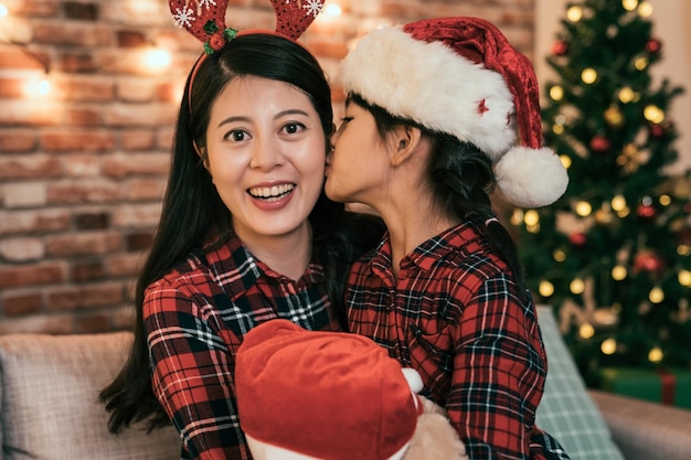 happy family mother and child daughter on Christmas eve at the Xmas tree with gifts. cute kid hugging and kissing her mom. both having fun and enjoying winter holidays together.