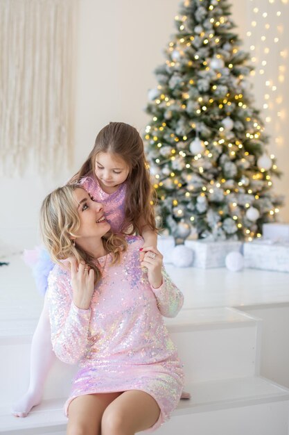 自宅のクリスマスツリーの近くで幸せな家族の母と子の娘