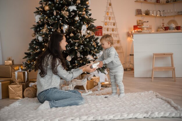 Happy family mother and child daughter near christmas tree at home