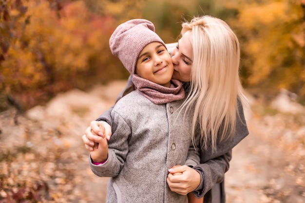 幸せな家族の母と子の娘は秋の散歩で遊び、笑います。母と子の関係。同じジャケットでおしゃれな雰囲気のおしゃれな母娘
